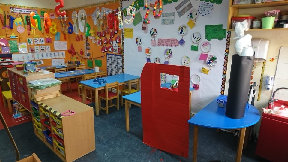 A colourful Early Years classroom with blue tables and displays